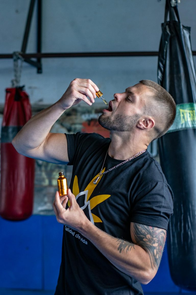 Athletic man in gym holds CBD oil, emphasizing fitness and wellness.