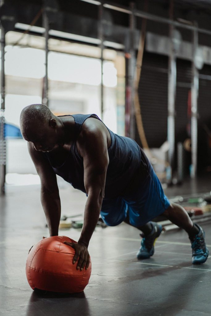 An adult man focuses on fitness with a push-up using a fitness ball in an indoor gym setting.